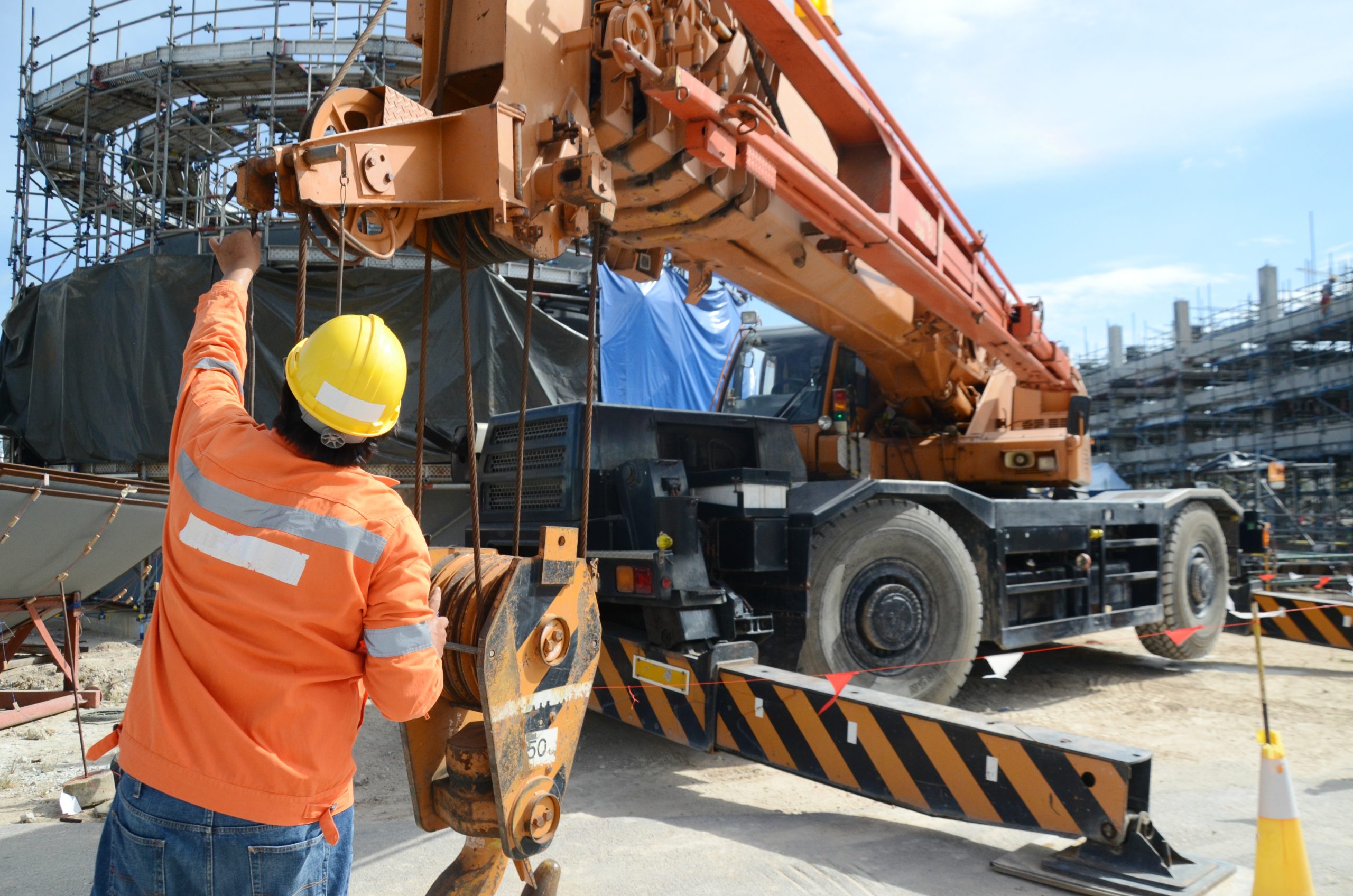 Crane operator in hi-vis signaling a truck-mounted crane on a job site